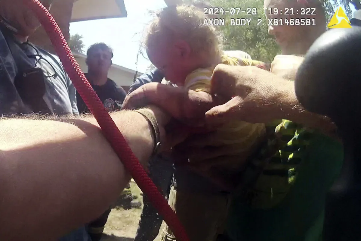 Emergency crews rescue a 14-month-old boy after he fell into a narrow pipe and got stuck around a dozen feet below ground in the yard of his home in Moundridge, Kan., on July 28, 2024. (Moundridge Police Department via AP)