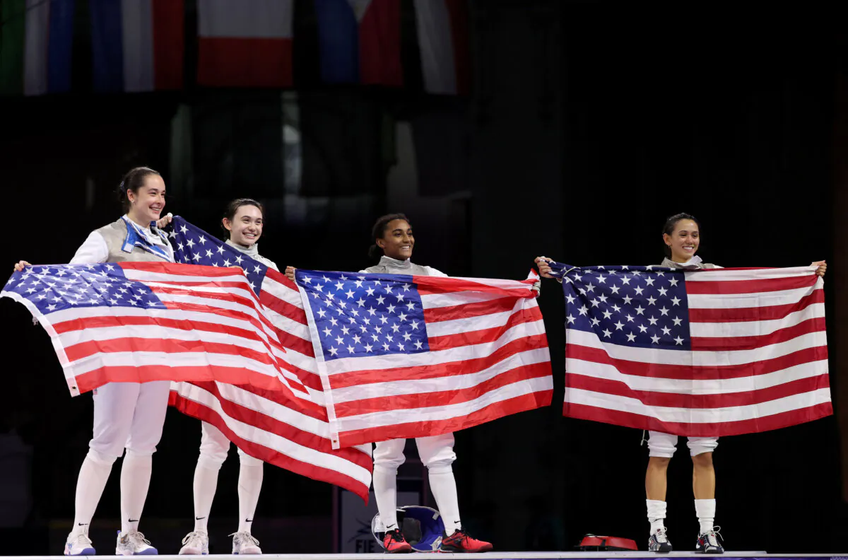 (L–R) Lee Kiefer, Lauren Scruggs, Jacqueline Dubrovich, and Maia Mei Weintraub of the United States celebrate with flags after winning the women's foil team gold medal bout between Italy and USA during the Paris 2024 Olympic Games at the Grand Palais in Paris, on Aug. 1, 2024. (Maye-E Wong/Reuters)