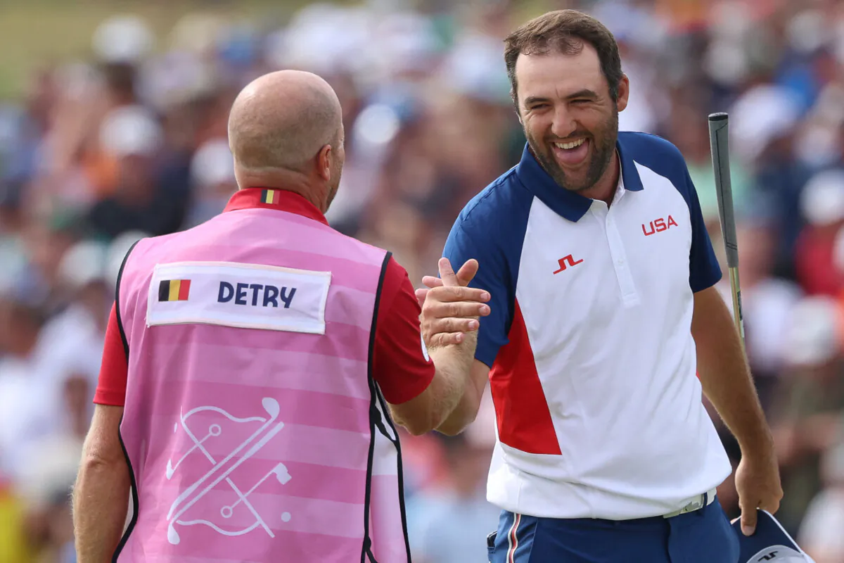 Scottie Scheffler greets Belgium's Thomas Detry's caddie after completing the course in round 4 of the men's golf individual stroke play of the Paris 2024 Olympic Games at Le Golf National in Guyancourt, south-west of Paris, on Aug. 4, 2024. (Emmanuel Dunand/AFP via Getty Images)