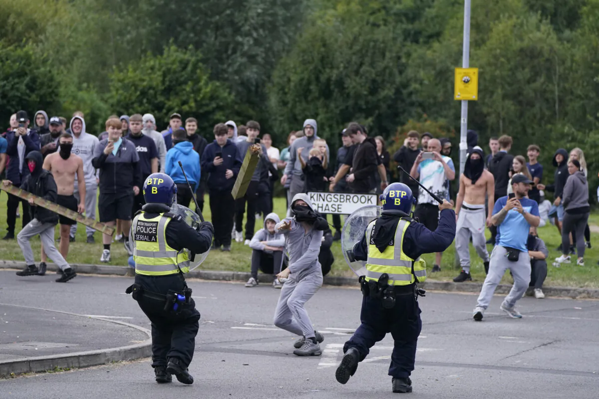 A youth throws a fence post towards police during an anti-immigration demonstration near the Holiday Inn Express in Rotherham, England, on Aug. 4, 2024. (Danny Lawson/PA Wire)