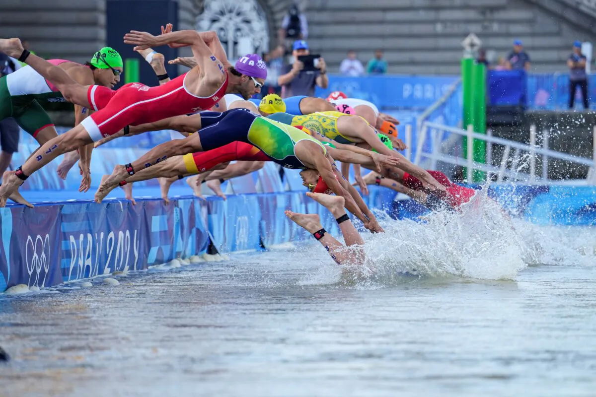 Athletes dive into the water for the start of the mixed relay triathlon at the 2024 Summer Olympics, in Paris on Aug. 5, 2024. (Vadim Ghirda)