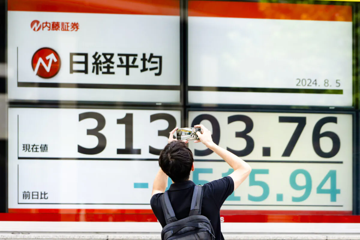 A pedestrian takes a photograph of monitors displaying the Nikkei 225 Stock Average figure outside a securities firm in Tokyo, Japan on Aug. 5, 2024. (Tomohiro Ohsumi/Getty Images)