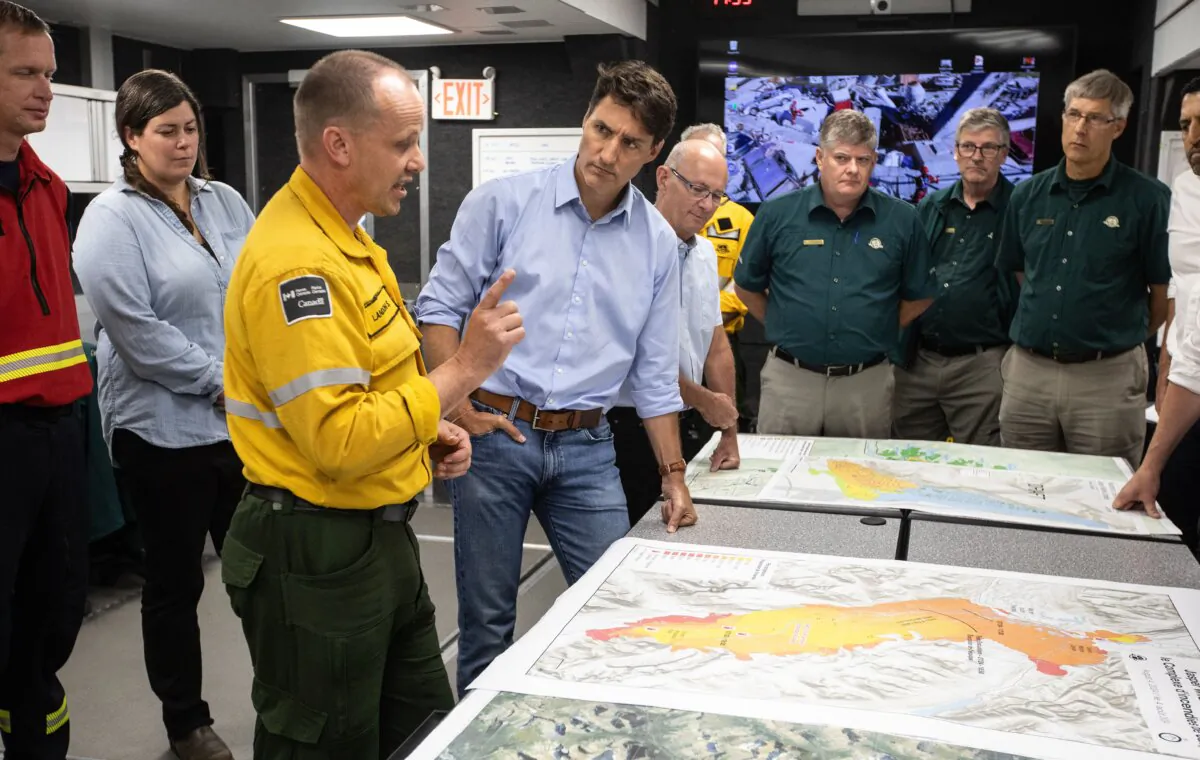 Wildfire Incident Commander Landon Shepherd (3rd L) and Prime Minister Justin Trudeau speak together while visiting the wildfire command centre in Hinton, Alta., on Aug. 5, 2024. (The Canadian Press/Jason Franson)