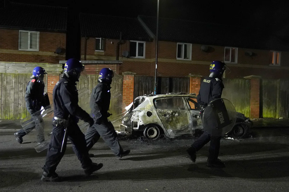 Police officers walk past a burnt out vehicle as they are deployed on the streets following a protest in Hartlepool, England, on July 31, 2024. (Owen Humphreys/PA)
