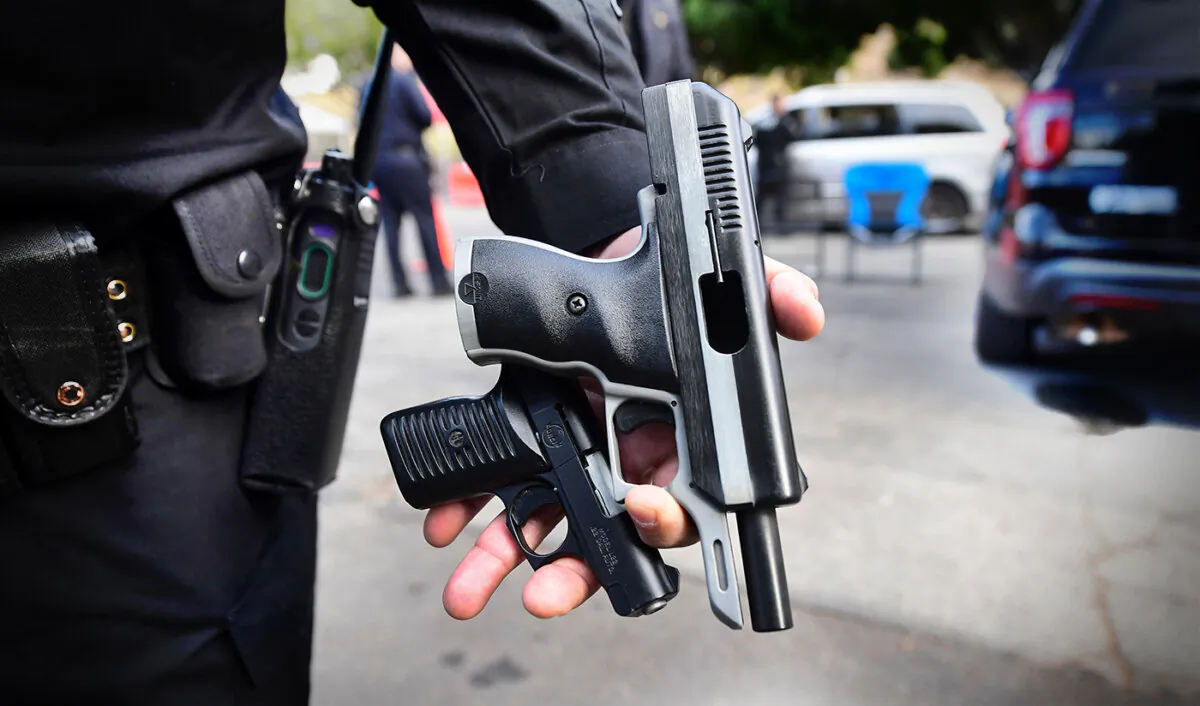A Los Angeles Police Department officer displays guns turned in by residents at a gun buy-back event taking place in three locations across Los Angeles on Dec. 5, 2020. (Frederic J. Brown/AFP via Getty Images)