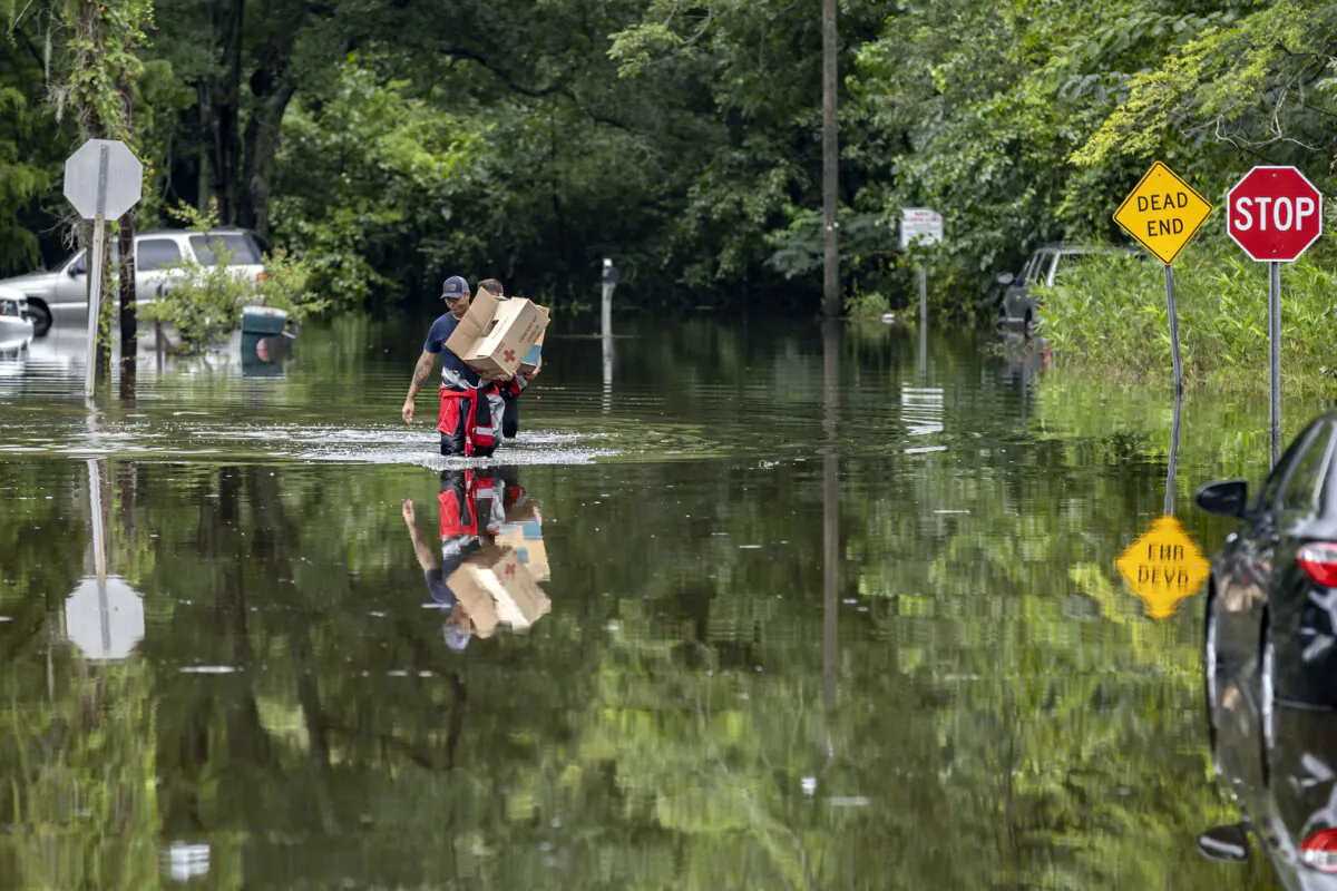 Savannah Fire Advanced Firefighters Andrew Stevenson, front, and Ron Strauss carry food to residents in the Tremont Park neighborhood that where stranded in flooding from Tropical Storm Debby, in Savannah, Ga., on Aug. 6, 2024. (Stephen B. Morton/AP Photo)