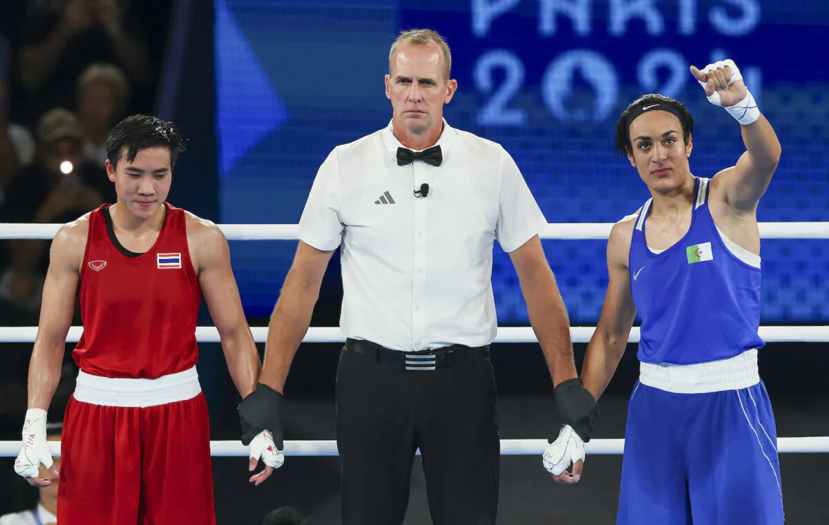 Janjaem Suwannapheng (L) of Team Thailand stands with match referee Shawn Reese and Imane Khelif (R) of Team Algeria as Khelif is declared winner of the Women's 66kg Semifinal round match on day eleven of the Olympic Games Paris 2024 at Roland Garros in Paris, France on Aug. 6, 2024. (Matthew Stockman/Getty Images)