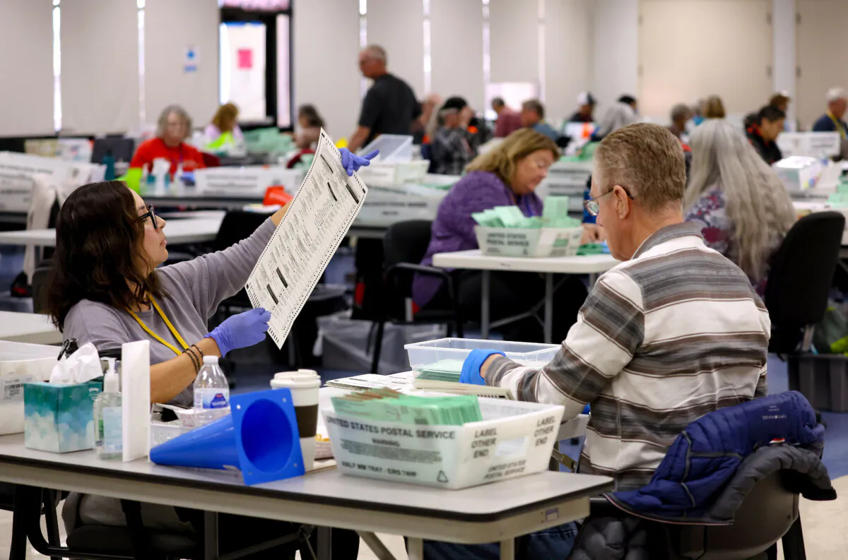 An elections worker inspects a mail-in ballot in Phoenix on Nov. 6, 2022. (Justin Sullivan/Getty Images)