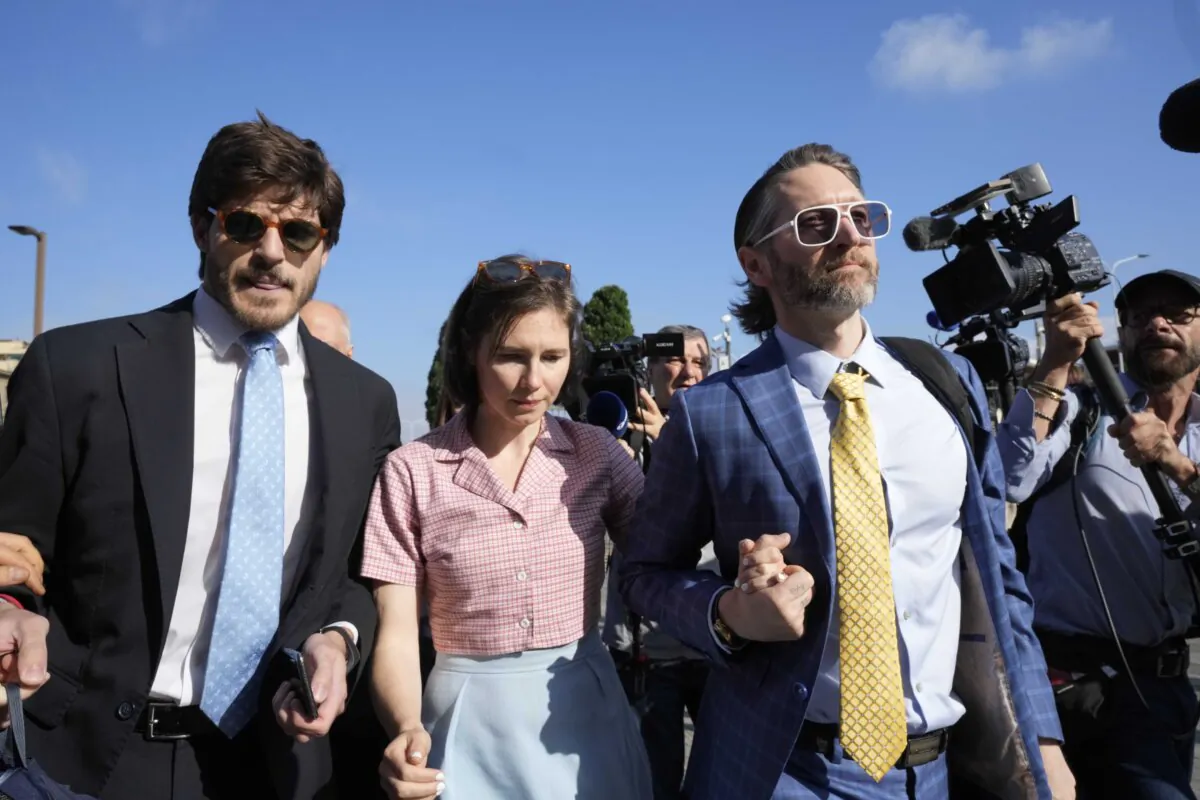 Amanda Knox arrives flanked by her husband, Christopher Robinson, right, and her lawyer, Luca Luparia Donati, left, at a court in Florence, Italy, June 5, 2024. (AP Photo/Antonio Calanni)