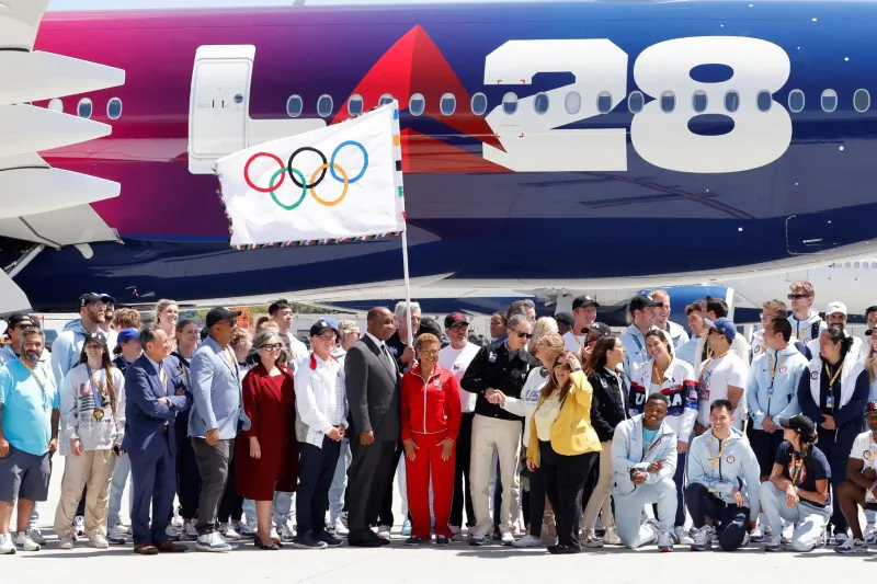 Members of LA28, local government officials and U.S. olympic athletes pose with the official Olympic flag as it returns to Los Angeles for the first time in 40 years, in Los Angeles on Aug. 12, 2024. (Carlin Stiehl/Reuters)