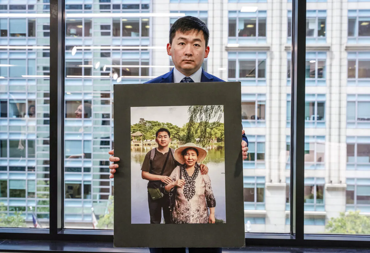 Simon Zhang, an architect in New York City, holds a photo of him and his mother, who was tortured to death in China, at a panel discussion marking the 25th year of the Chinese Communist Party’s persecution of Falun Gong, in Washington, on July 17, 2024. (Caroline Li/The Epoch Times)