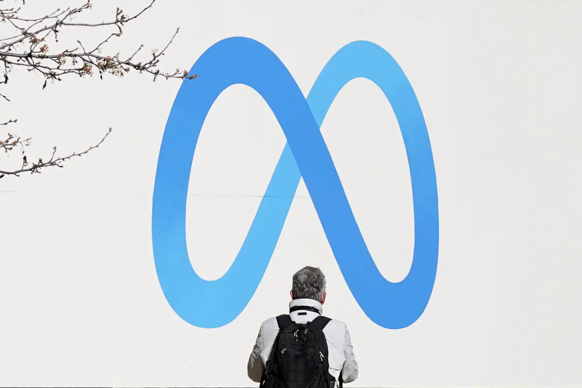 A person stands in front of a Meta sign outside of the company's headquarters in Menlo Park, Calif., March 7, 2023. (AP Photo/Jeff Chiu)