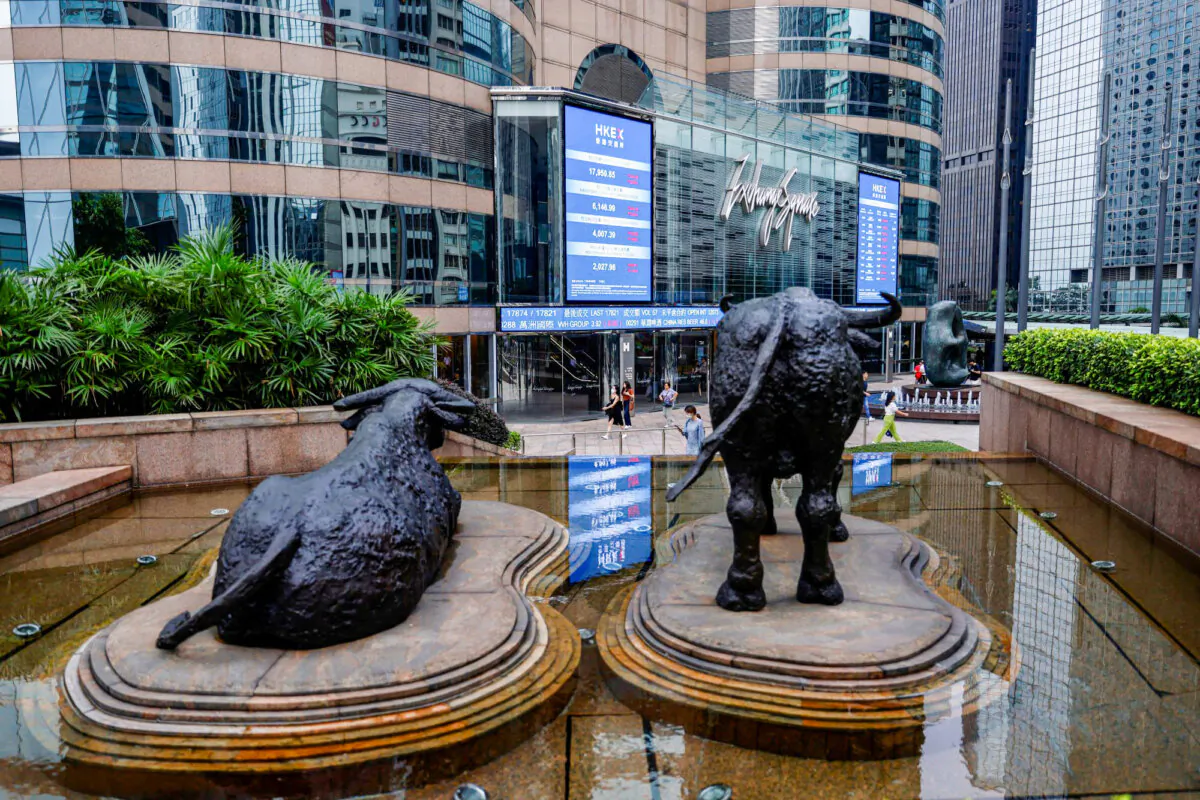 Bull statues are placed in front of screens showing the Hang Seng stock index and stock prices outside Exchange Square, in Hong Kong on Aug. 18, 2023. (Tyrone Siu/Reuters)