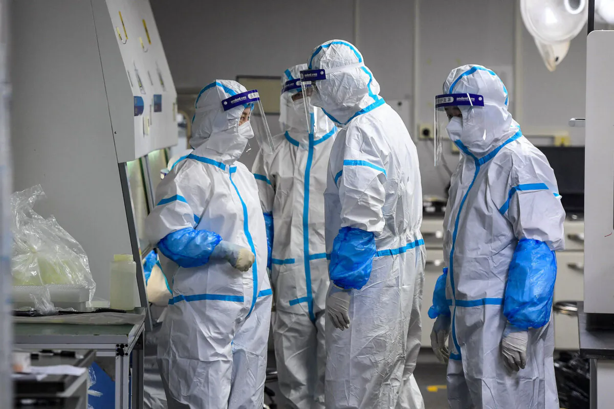 Laboratory technicians wearing personal protective equipment working on samples to be tested for COVID-19 at the Fire Eye laboratory, a COVID-19 testing facility, in Wuhan in China's central Hubei Province, on Aug. 4, 2021. (STR/AFP via Getty Images)
