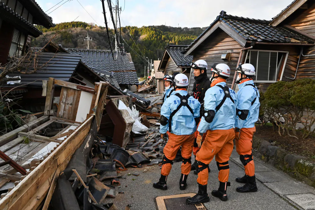 Firefighters inspect collapsed wooden houses in Wajima, Ishikawa prefecture, on Jan. 2, 2024, a day after a major 7.5 magnitude earthquake struck the Noto region in Ishikawa prefecture. (Kazuhiro Nogi/AFP via Getty Images)