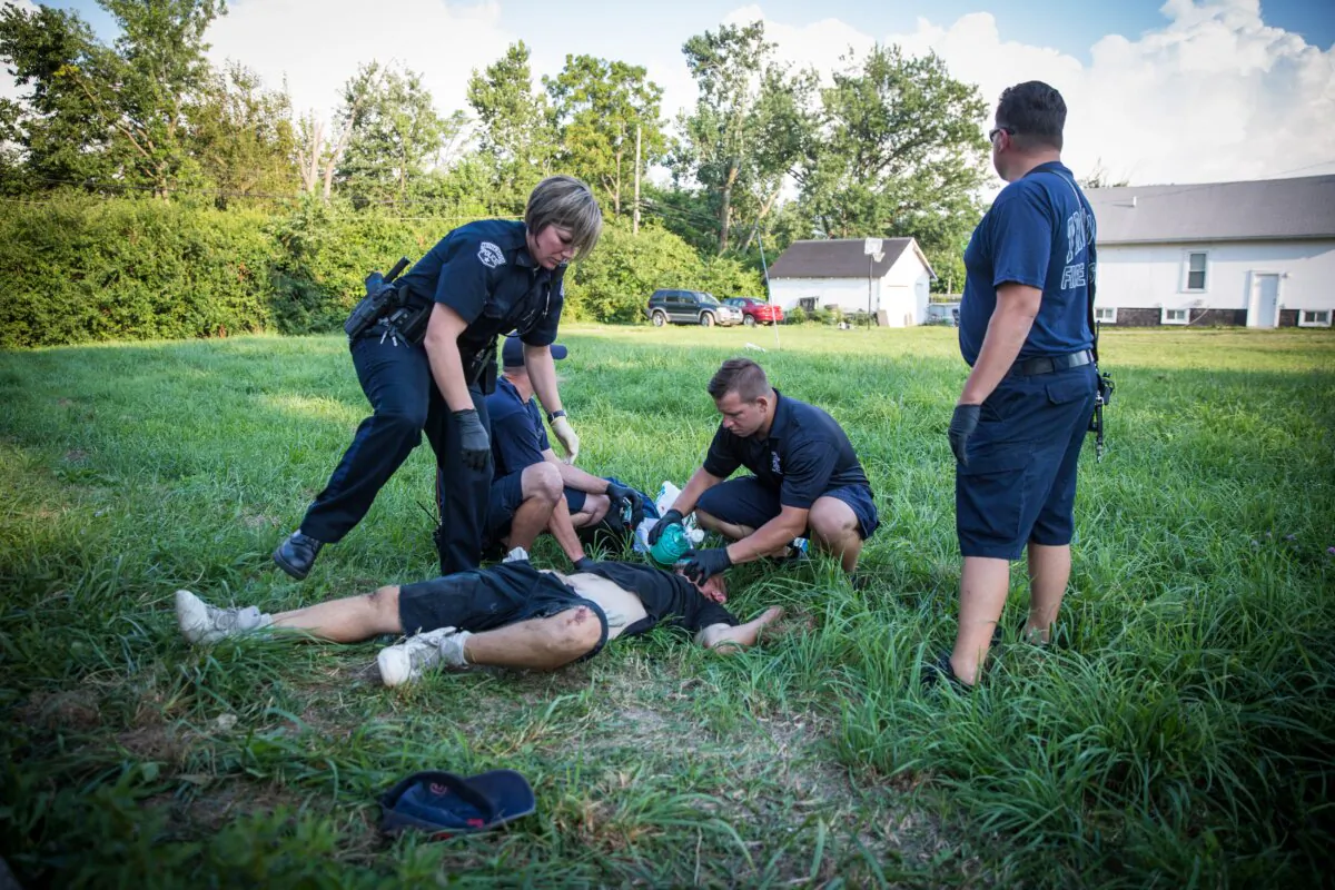 Local police and paramedics help a man who is overdosing in the Drexel neighborhood of Dayton, Ohio, on Aug. 3, 2017. (The Epoch Times)