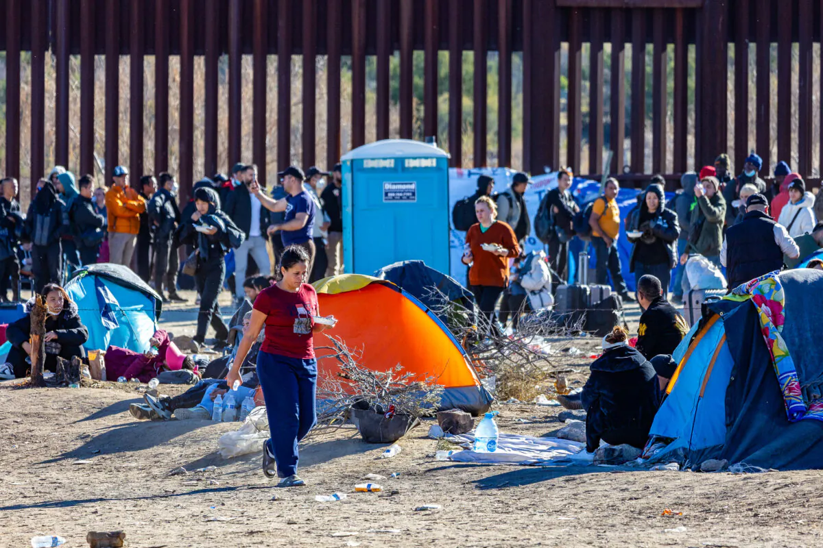 Illegal immigrants who passed through a gap in the U.S. border wall await processing by Border Patrol agents in Jacumba, Calif., on Dec. 7, 2023. (John Fredricks/The Epoch Times)
