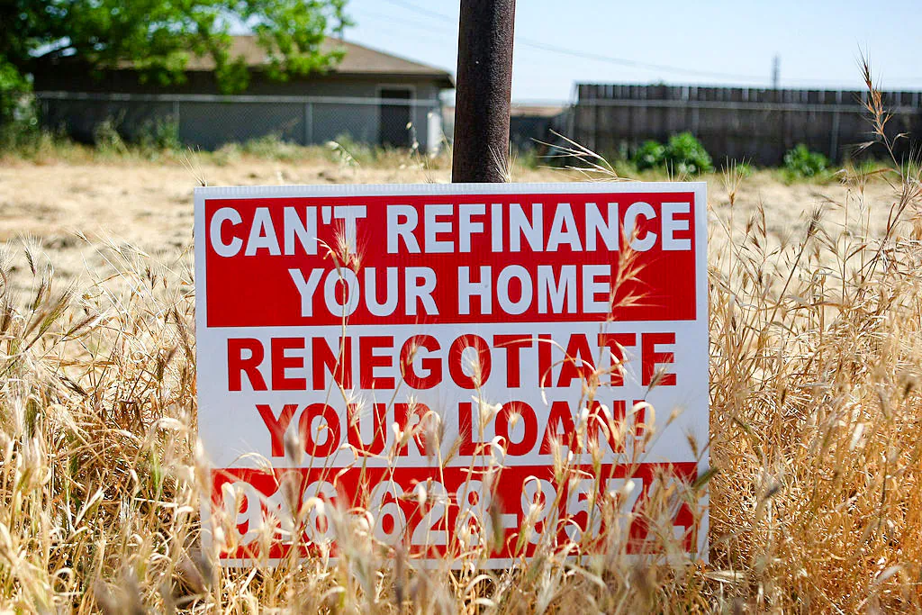 A sign advertising refinancing services is posted in a vacant lot in Stockton, Calif., on April 29, 2008. (Justin Sullivan/Getty Images)