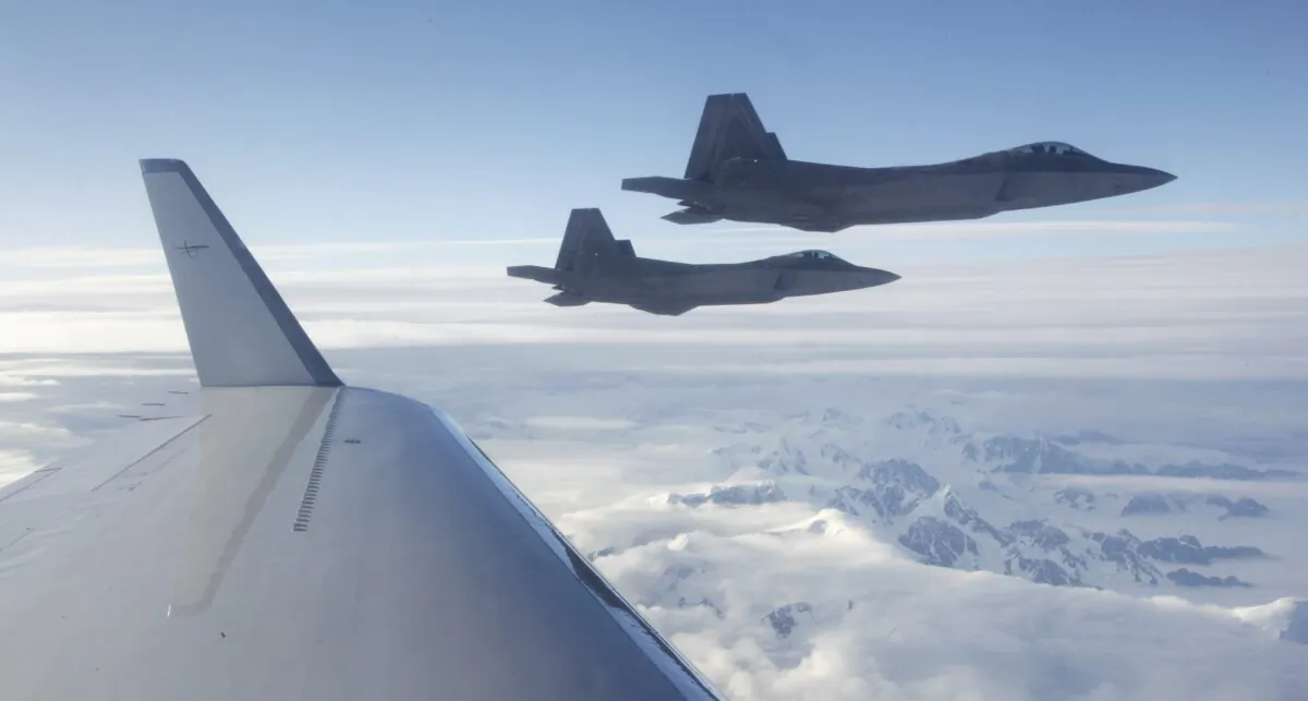 A pair of U.S.-built NORAD F-22 fighter jets fly off the wing of a civilian airplane playing the role of a hijacked airliner over a mountainous area of Alaska, on Aug. 10, 2010. (AP Photo/Ted S. Warren)