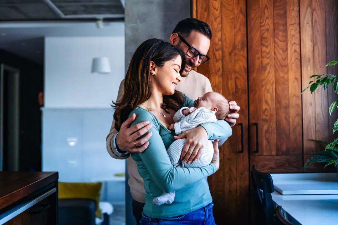A father and mother with their newborn baby at home in a photo file. (Shutterstock/NDAB Creativity)