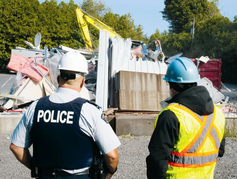 An RCMP officer and a worker look on the demolition of the temporary installation for refugee claimants at Roxham Road Monday, in St. Bernard-de-Lacolle, Que., on Sept. 25, 2023. (The Canadian Press/Ryan Remiorz)