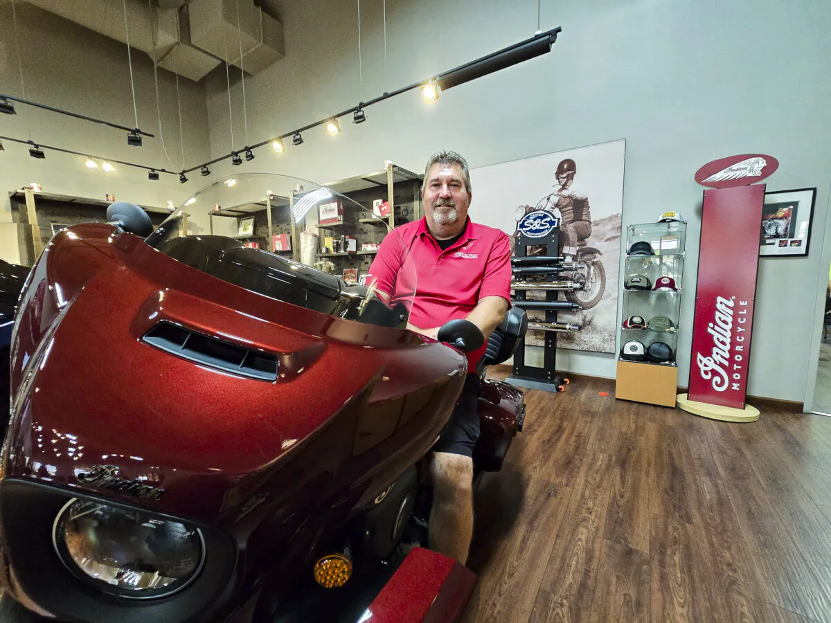 Quinn Keefe, marketing manager at Indian Motorcycle Peoria, sits on a Scout, one of the dealership's most popular models, in Peoria, Ariz., on Aug. 21, 2024. (Allan Stein/The Epoch Times)