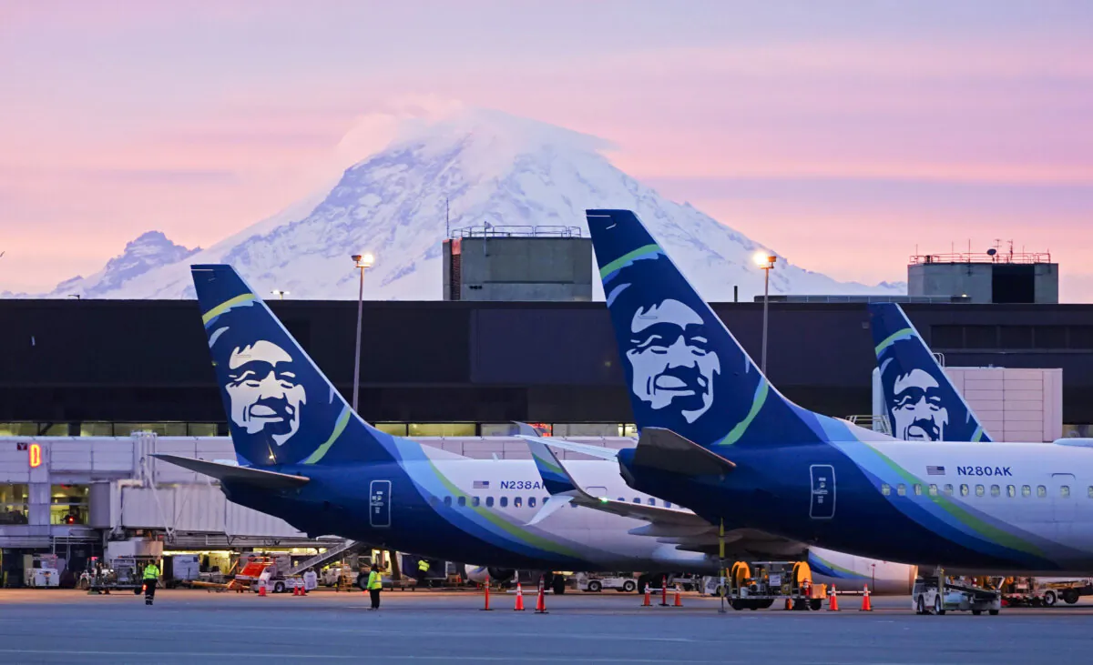 Alaska Airlines planes are parked at gates with Mount Rainier in the background at sunrise, at Seattle-Tacoma International Airport in Seattle on March 1, 2021. (Ted S. Warren/AP Photo)