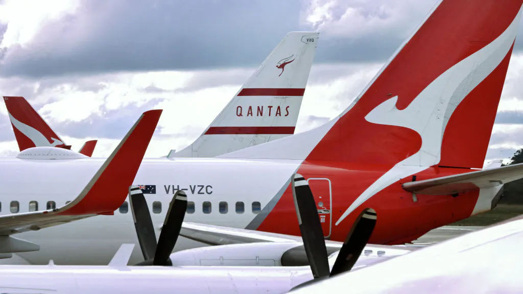 A photo taken on June 26, 2024 shows the vertical stabiliser of a Qantas Boeing 737-800 aircraft painted in heritage livery (background C) seen past other Qantas planes parked at a terminal at Melbourne's Tullamarine Airport. (William West/AFP via Getty Images)
