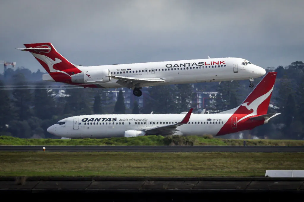 A Qantas Airlines Boeing 737-800 plane travels down the runway as a Qantas Boeing 717 plane lands at Sydney International Airport on June 7, 2024. (DAVID GRAY/AFP via Getty Images)