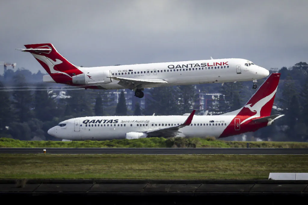 A Qantas Airlines Boeing 737-800 plane travels down the runway as a Qantas Boeing 717 plane lands at Sydney International Airport on June 7, 2024. (David Gray/AFP via Getty Images)