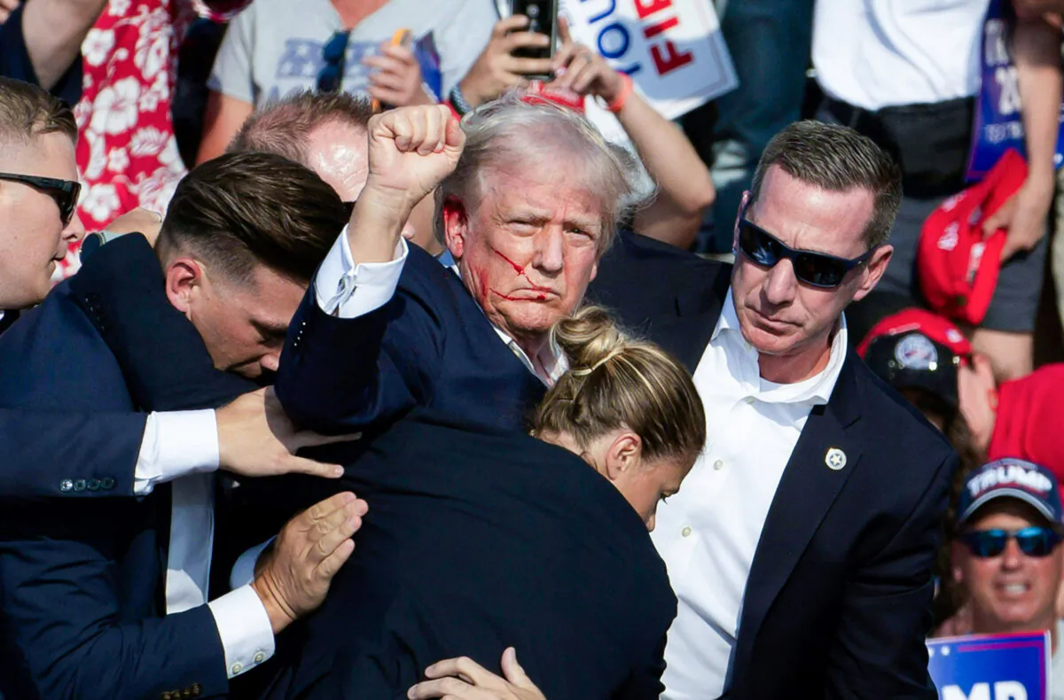 Former President Donald Trump is surrounded by Secret Service agents after being shot by would-be assassin Thomas Crooks at a rally in Butler, Pa., on July 13, 2024. (Rebecca Droke/AFP via Getty Images)