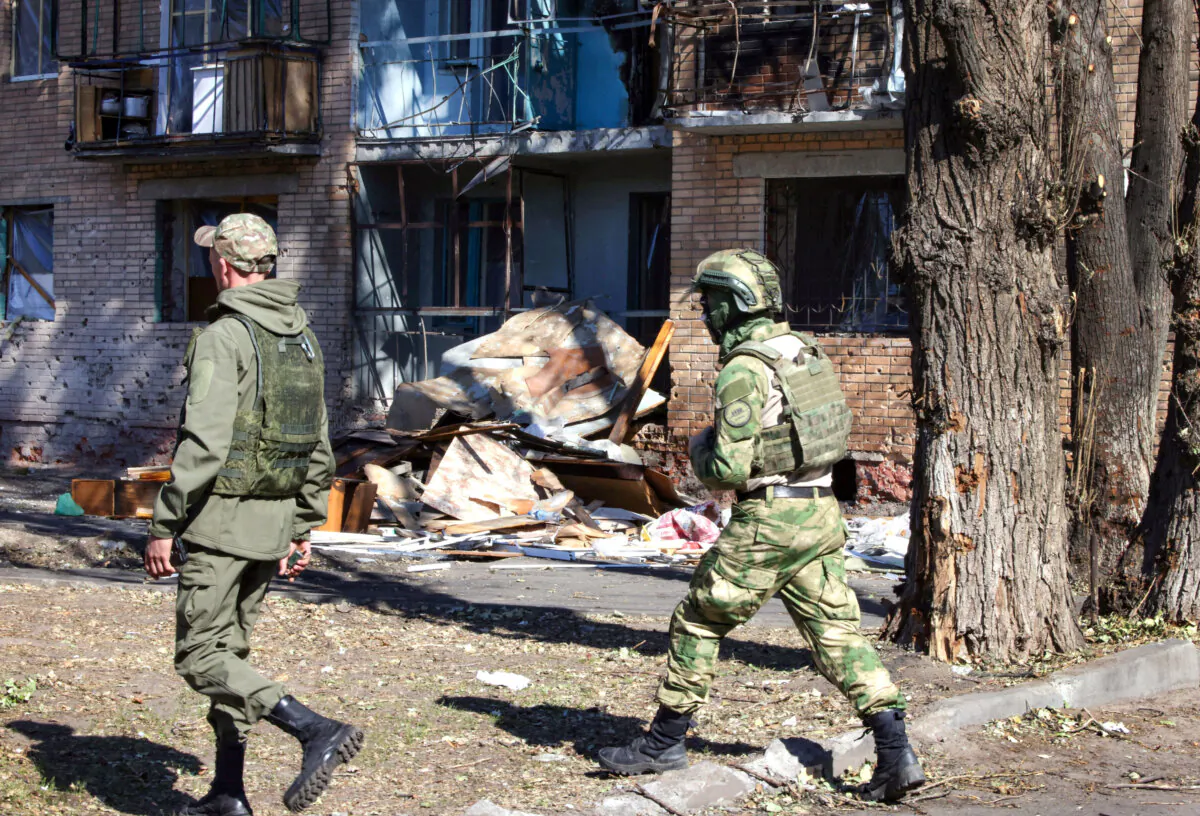 Local volunteers walk past a building damaged by Ukrainian strikes in Kursk, Russia, on Aug. 16, 2024. (Tatyana Makeyeva/AFP via Getty Images)