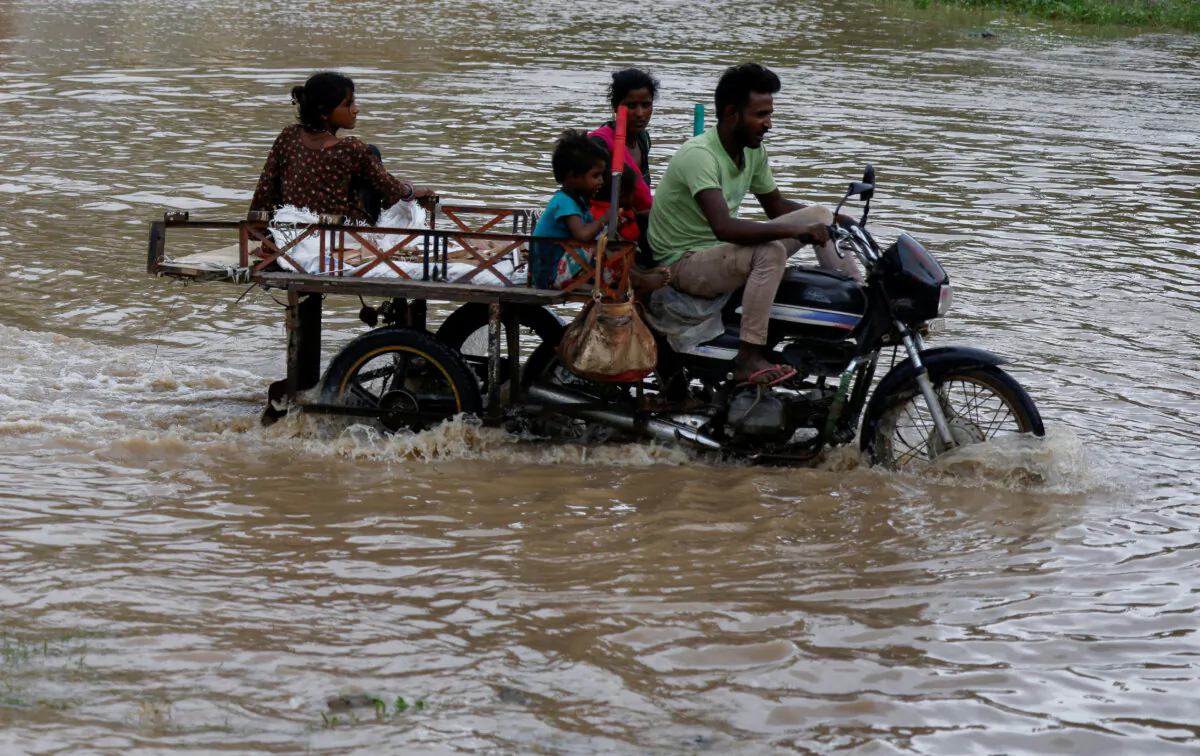 A family crosses a flooded street after heavy rains in Ahmedabad, India, August 28, 2024. (Amit Dave/Reuters)