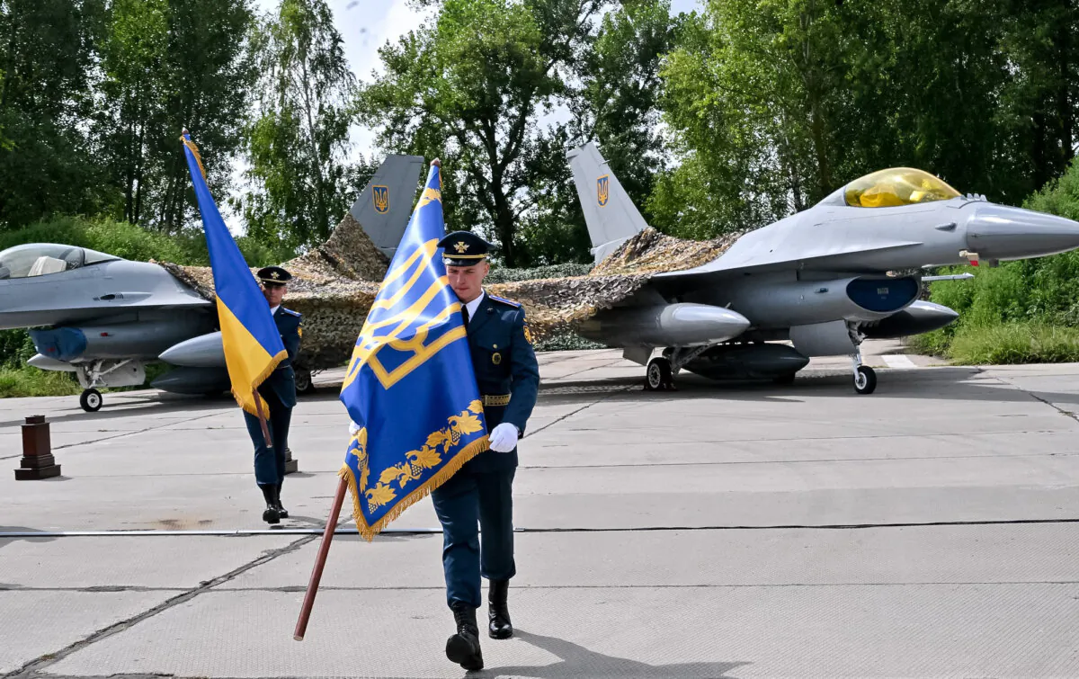Ukrainian servicemen carry flags after a ceremony held to mark Ukrainian Air Forces Day at an undisclosed area on Aug. 4, 2024. (Sergei Supinsky/AFP)