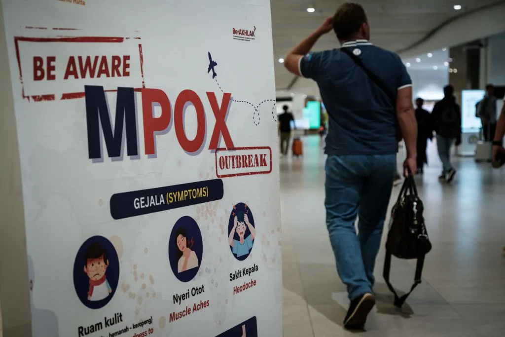 A passenger walks past a banner informing about Monkeypox (MPOX) at Soekarno-Hatta International Airport in Tangerang, Indonesia, on Aug. 26, 2024. (YASUYOSHI CHIBA/AFP via Getty Images)