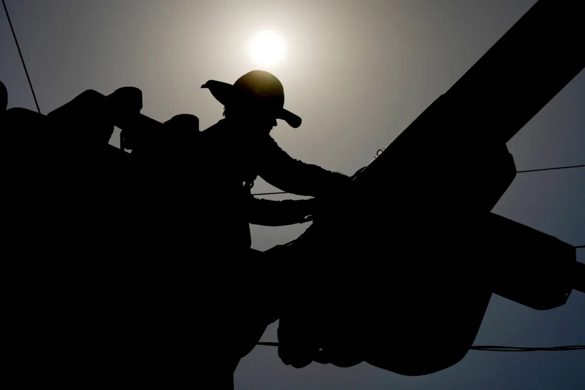 A linesman works on power lines under the morning sun, in Phoenix on July 12, 2024. (Matt York/AP Photo)