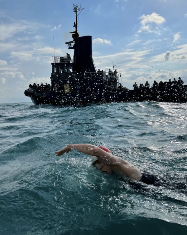 woman swimming with tugboat in background in Young Woman and the Sea
