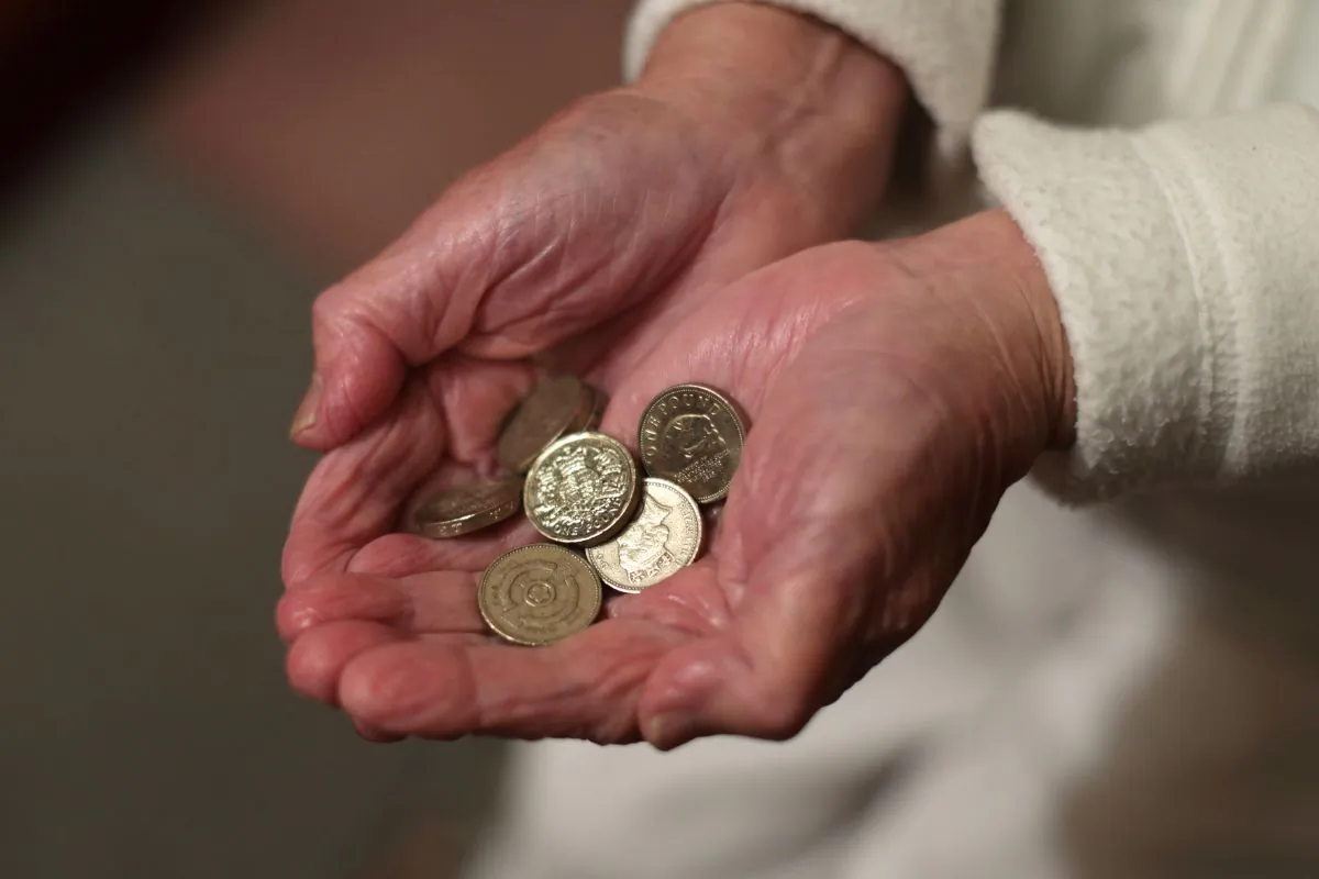 An elderly woman holding pound coins in her hands, in Poole, Dorset, England, on Dec. 22, 2016. (Yui Mok/PA Wire)