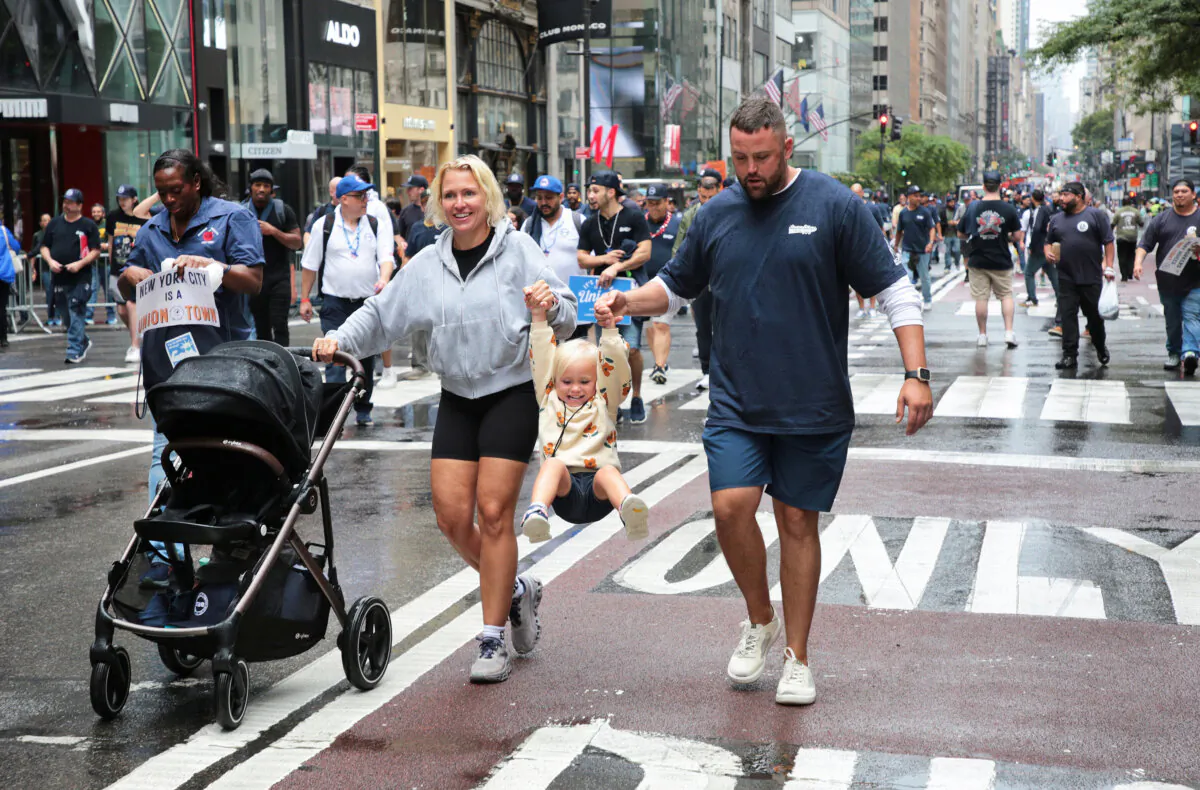 A parade is even more fun when your parents allow you to swing on Fifth Avenue during the annual Labor Day Parade in New York City on Sept. 7, 2024. (Richard Moore/The Epoch Times)