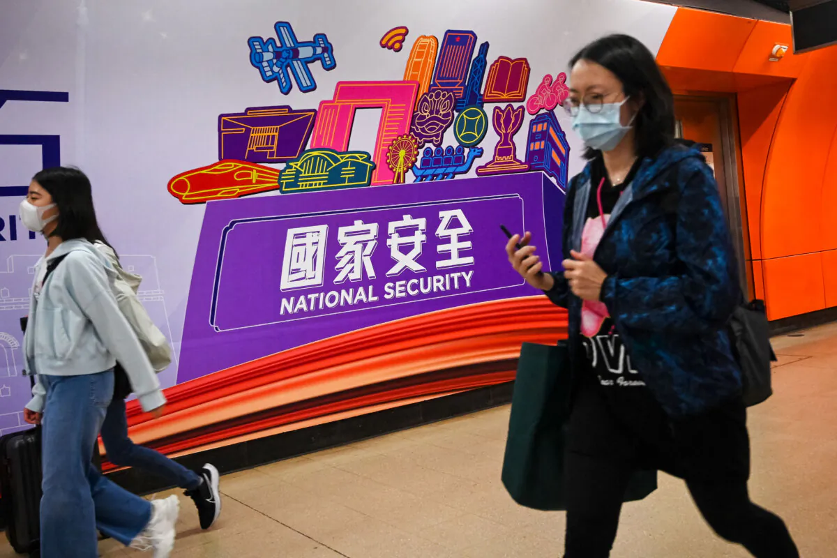 People walk past a National Security banner at a train station on National Security Education Day in Hong Kong on April 15, 2023. (Peter Parks/AFP via Getty Images)