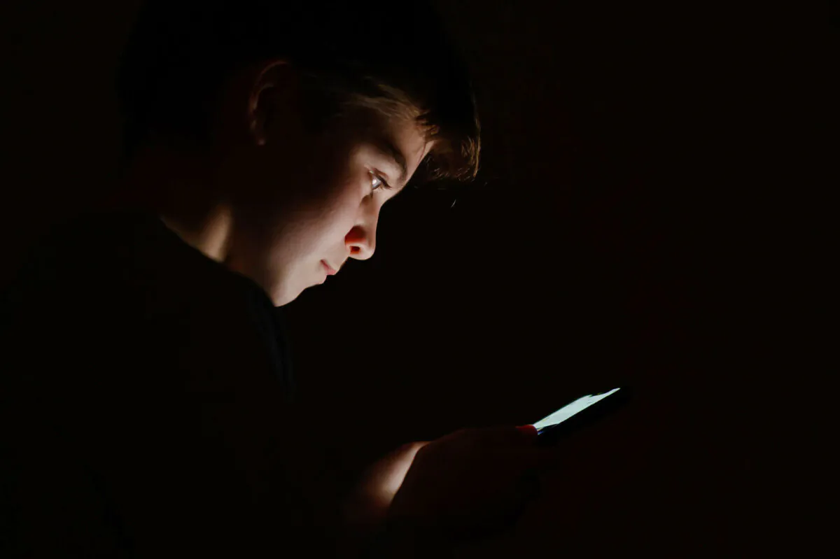In this photo illustration, a teenage child looks at the screen of a mobile phone in London on Jan. 17, 2023. (Leon Neal/Getty Images)