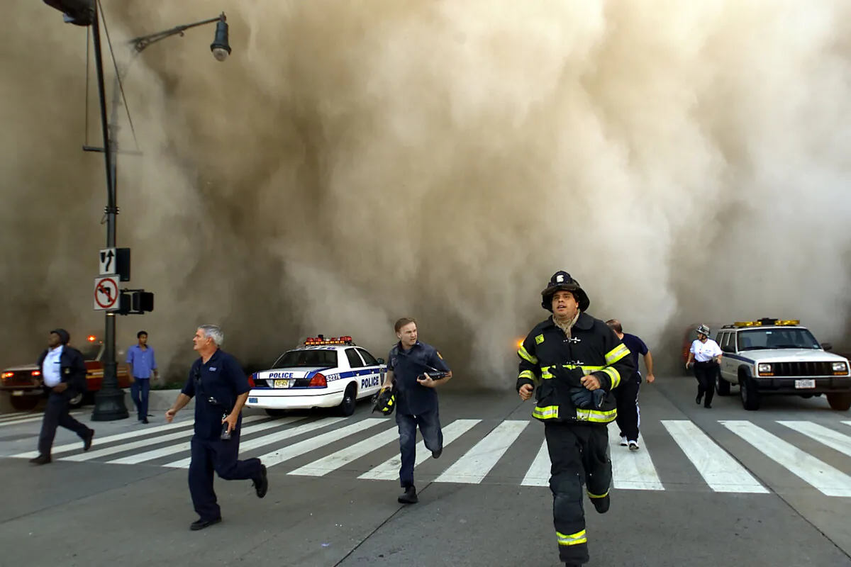 Policemen and firemen run away from the huge dust cloud caused by the World Trade Center's Tower One collapsing after terrorists crashed two hijacked planes into the twin towers, in New York City on Sept. 11, 2001. (Jose Jimenez/Primera Hora/Getty Images)