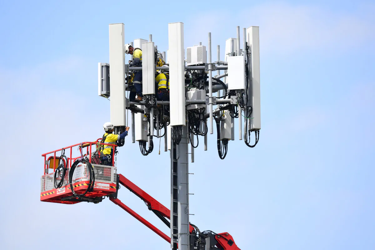 Telecommunications workers are seen working on a mobile cell tower in Sydney, Australia, on March 25, 2020. (AAP Image/Dan Himbrechts)