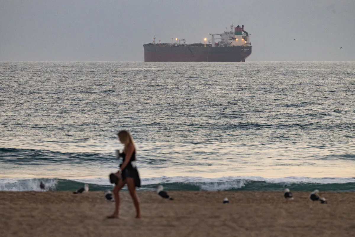 Beachgoers enjoy the ocean in view of oil shipment and production vessels in Huntington Beach, Calif., on Sept. 12, 2024. (John Fredricks/The Epoch Times)