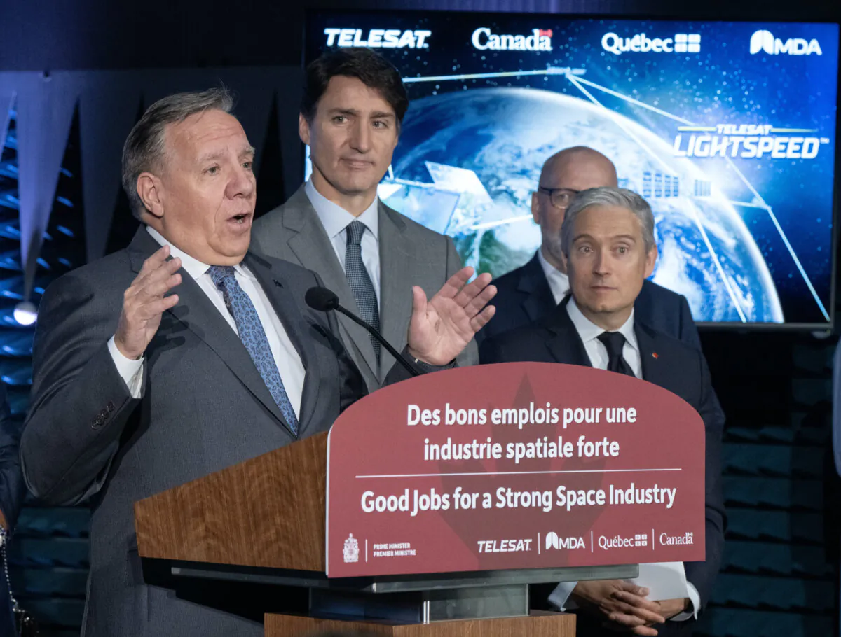 Quebec Premier Francois Legault speaks to the media as Prime Minister Justin Trudeau and federal Industry Minister Francois-Philippe Champagne look on during an aerospace announcement at the MDA satellite manufacturing centre in Ste.Anne-de-Bellevue, Quebec, on Sept. 13, 2024. (The Canadian Press/Ryan Remiorz)