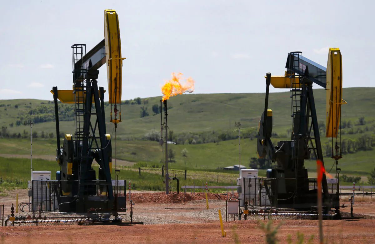 Oil is pumped and natural gas is flared off on an oilfield near Watford City, N.D., on June 12, 2014. (Charles Rex Arbogast/AP Photo)