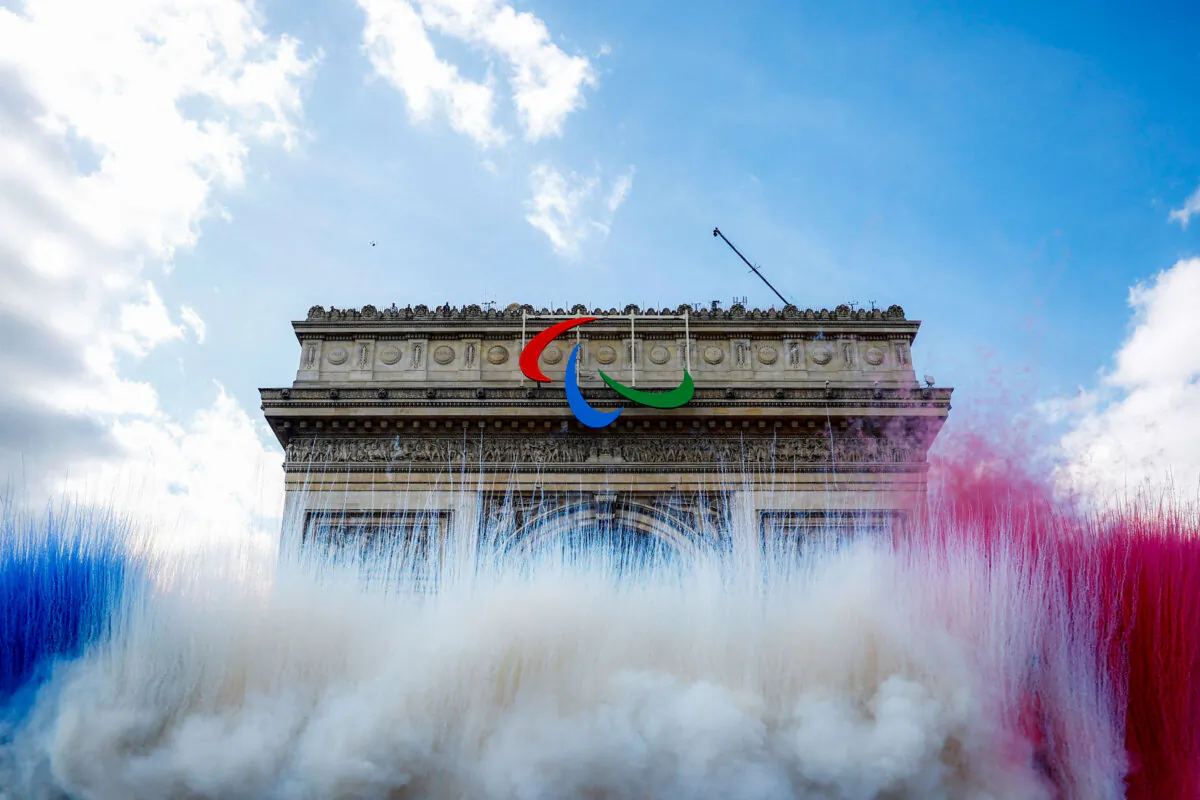 Smoke in the colours of French national flag rises near the Arc de Triomphe on the day of a parade of French athletes who competed in the Paris 2024 Olympic and Paralympic Games in Paris, on Sept. 14, 2024. (Sarah Meyssonnier/POOL/AFP via Getty Images)