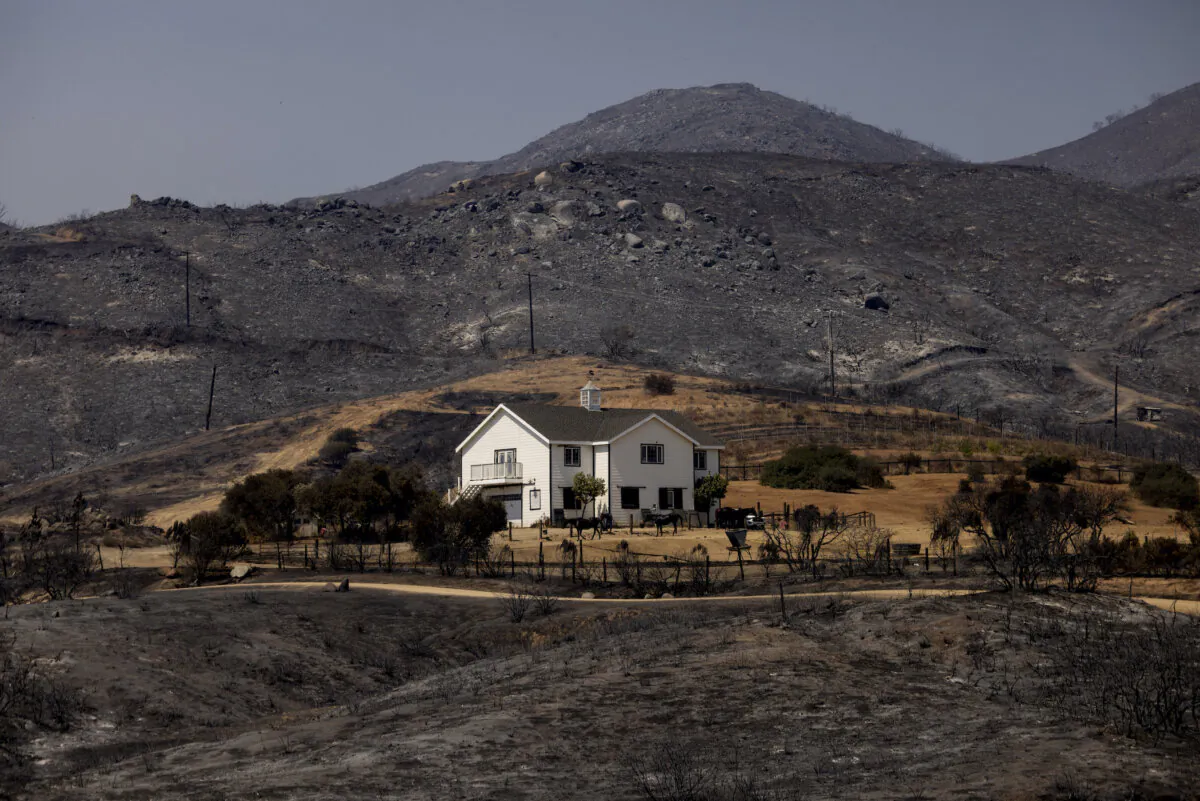 A house untouched by flames amid scorched hills in the village of El Cariso near Lake Elsinore, Calif., on Sept. 12 after the Airport fire raced through. (Etienne Laurent/AFP via Getty Images)