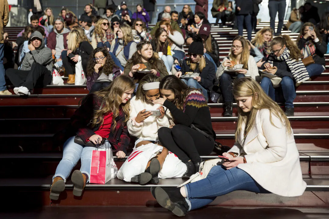 A group of teens look at a photograph they took on a smartphone in Times Square in New York City, on Dec. 1, 2017. (Drew Angerer/Getty Images)
