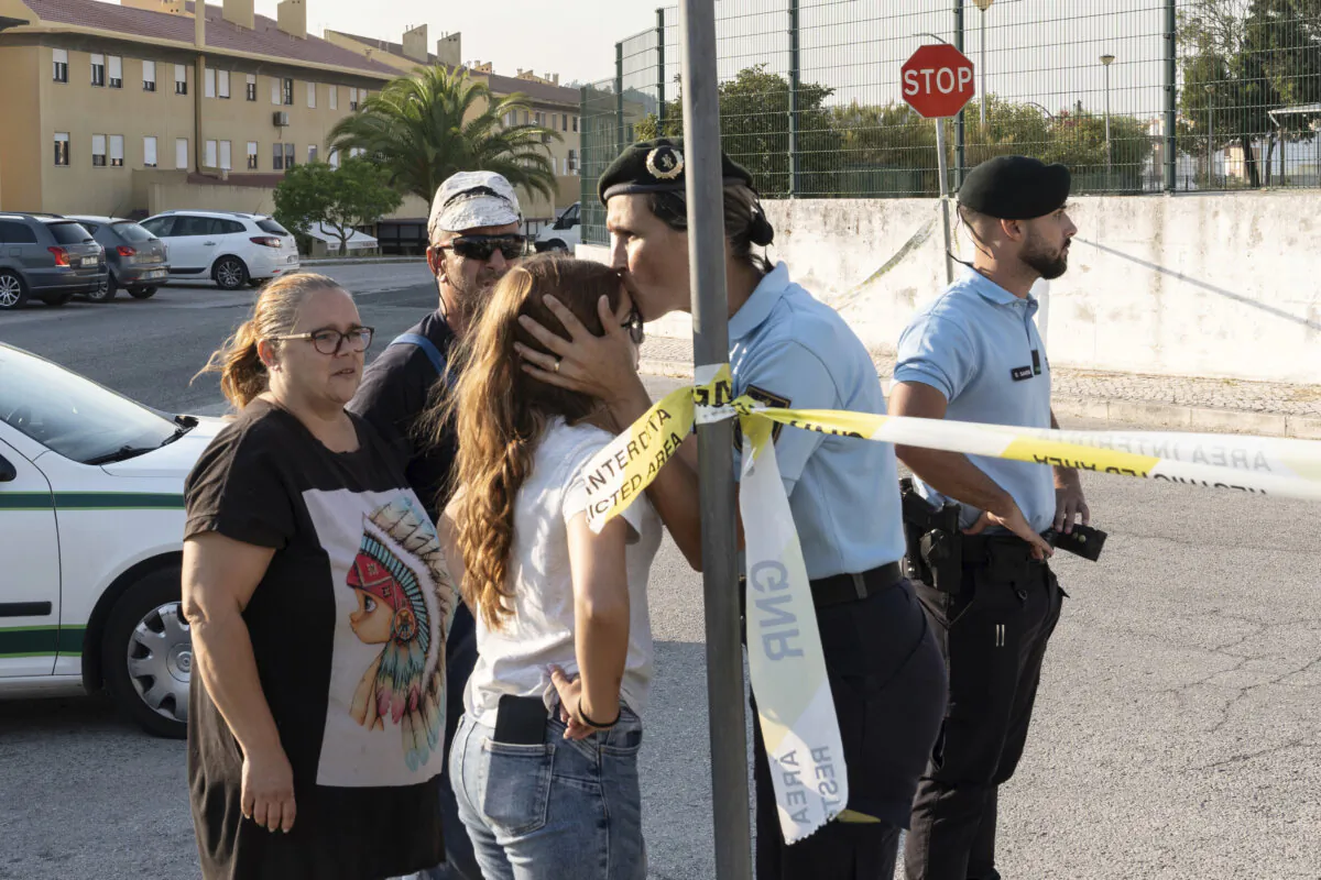 A police officer kisses a girl outside a school following a stabbing attack in Azambuja near Lisbon, Tuesday, Sept. 17, 2024. (Ana Brigida/AP Photo)